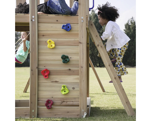 Kinder spielen auf einem Holzspielplatz mit Kletterwand, Leiter und Schaukel.