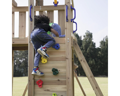 Kind klettert auf ein hölzernes Spielgerät mit Kletterwand