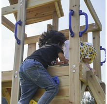 Kinder klettern auf einem hölzernen Spielturm mit blauen Griffen und Klettersteinen.