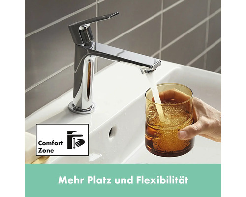 Wasserhahn aus Chrom füllt ein Glas Wasser in einem Waschbecken