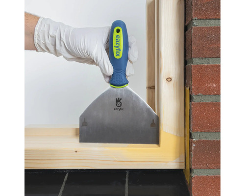 Hand mit Spachtel beim Verfugen eines Holzrahmens