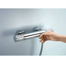 Aufputz-Thermostatbatterie mit Hand darunter an der Wand