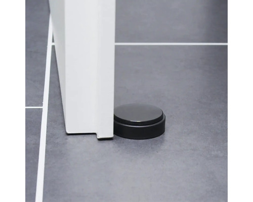 Schwarzer Türstopper neben einer Tür auf gefliestem Boden