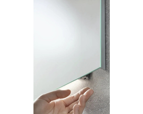 Rechteckiger Badezimmerspiegel mit Licht und Hand im Bild.