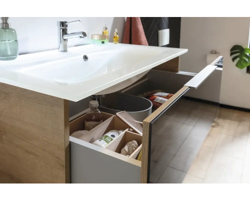 Badezimmerwaschtisch mit geöffneter Schublade, die Kosmetikartikel und einen Eimer zeigt