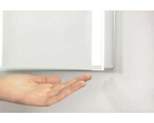 Detailansicht eines Spiegelschranks mit einer Hand im Vordergrund