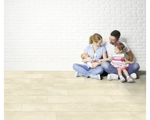 Familie sitzt auf hellem Laminatboden vor einer weißen Ziegelwand