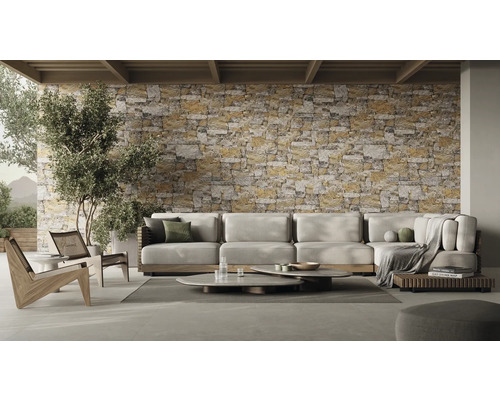 Wohnzimmer mit Ecksofa, Couchtischen und Steinwand