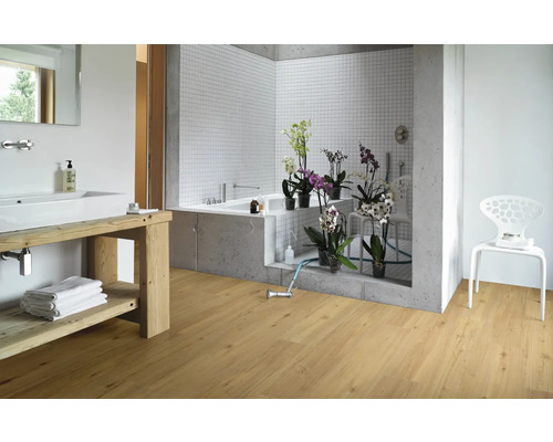 Helles Badezimmer mit Holzboden, Waschbecken mit Holzunterschrank, Badewanne und weißem Stuhl.