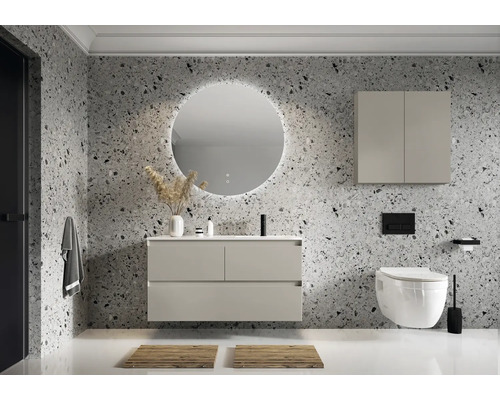 Modernes Badezimmer mit Waschtisch, beleuchtetem Spiegel, Hängeschrank und WC vor einer Wand mit Steinmuster