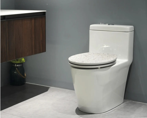 Weißes Stand-WC mit Spülkasten und Dekor auf dem Toilettendeckel im Badezimmer.