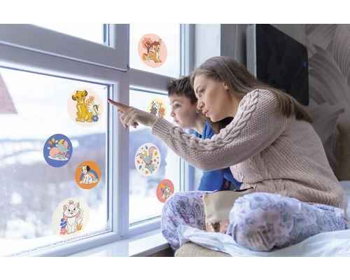 Mutter und Kind betrachten Fensteraufkleber mit Tiermotiven auf einer Fensterscheibe