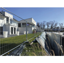 Baustelle mit Bauzaun und Rohbau eines Hauses