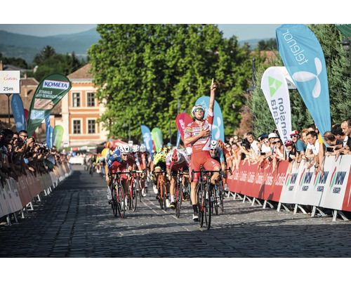 Radrennfahrer feiert den Sieg auf der Zielgeraden umgeben von Zuschauern