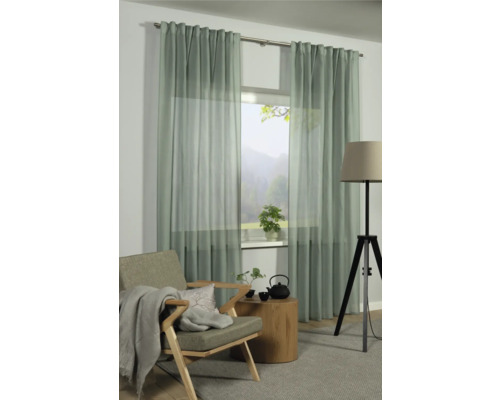 Helle Wohnzimmerszene mit Fenster, Vorhängen, Sessel, Tisch und Stehlampe