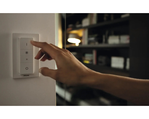 Eine Hand bedient einen Lichtschalter zur Steuerung der Beleuchtung.