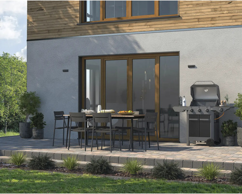 Terrasse mit Gartentisch, Stühlen und Grill vor einem Wohnhaus.