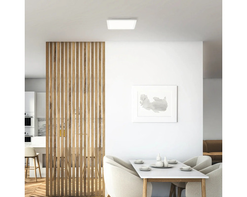 Helle Inneneinrichtung mit quadratischer Deckenleuchte, Holztrennwand und Esstisch.