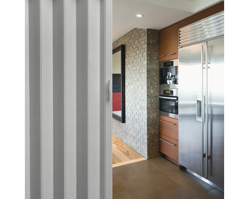 Faltbare Tür in einem Küchenbereich mit Geräten aus rostfreiem Stahl und Backsteinmauer