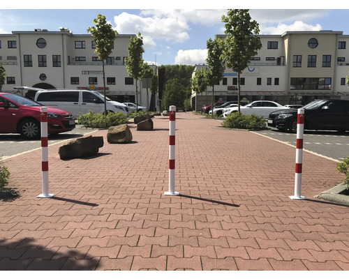 Sperrpfosten auf einem gepflasterten Weg mit parkenden Autos im Hintergrund