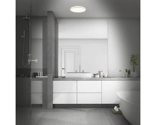 Modernes Badezimmer mit Dusche, Waschbecken, Spiegel, Badewanne und runder Deckenleuchte.