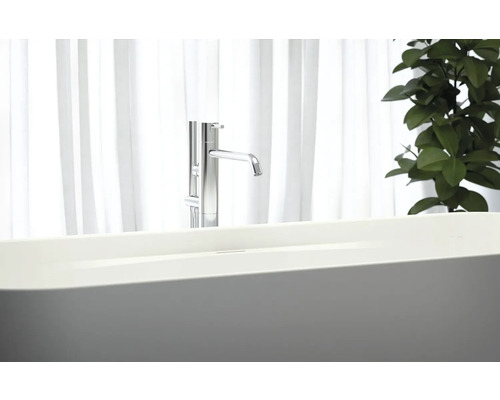 Freistehende Badewanne mit Armatur vor einem Fenster