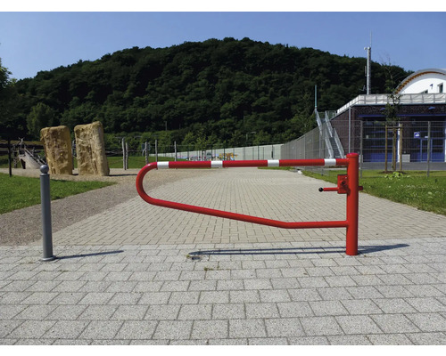 Eine rot-weiß gestreifte Schranke auf einem gepflasterten Weg in einem Außenbereich.