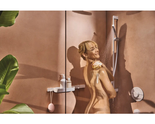 Frau unter der Dusche mit Duschkopf und Ablage