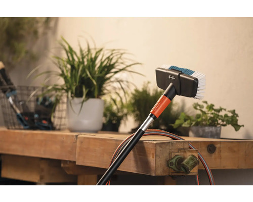 Gardena Waschbürste mit Wasseranschluss vor Pflanzen auf einer Werkbank