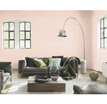 Wohnzimmer mit Sofa, Sessel, Holztisch und Bogenlampe vor rosa gestrichener Wand