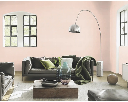 Wohnzimmer mit Sofa, Sessel, Holztisch und Bogenlampe vor rosa gestrichener Wand