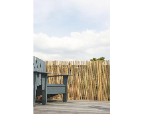 Szene mit einem grauen Gartenstuhl und einem Bambuszaun im Hintergrund.