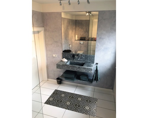 Badezimmer mit Waschbecken, Spiegel und gemusterter Badematte