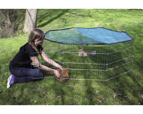 Frau mit Kaninchengehege im Freien mit Sonnenschutznetz