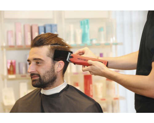 Ein Friseur schneidet einem Mann mit einem Haarschneider die Haare.