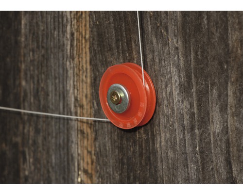 Eine Umlenkrolle mit Drahtseil an einer Holzwand