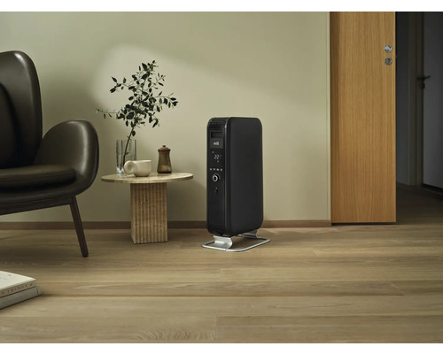 Schwarzer mobiler Heizkörper im Wohnzimmer neben Sessel und Tisch.