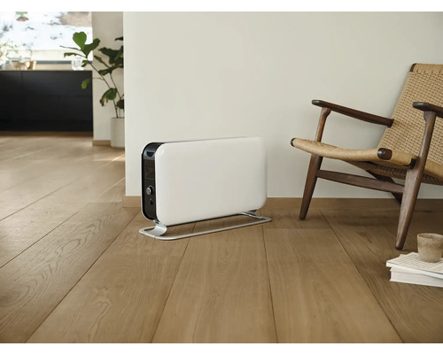 Weißer Heizkörper neben einem Stuhl in einem hellen Raum.