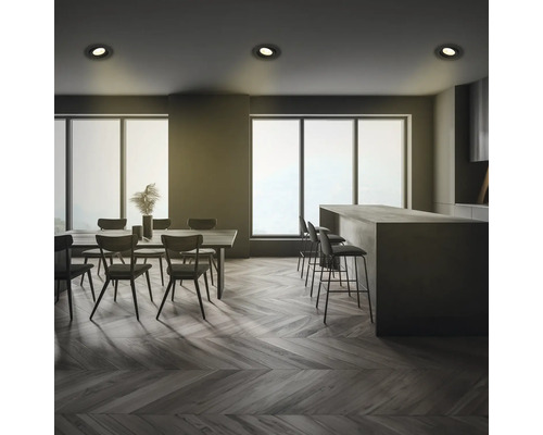 Innenaufnahme eines Essbereichs und einer Küche mit Tischen, Stühlen, Barhockern und Deckenleuchten