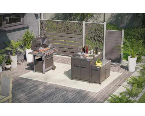Gartenszene mit Grill, Grillküche und Sichtschutzelementen auf einer Terrasse.