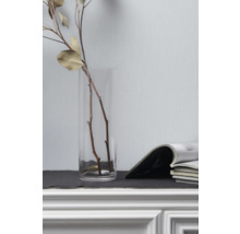 Dekorative Äste in Glasvase neben Zeitschriften auf Kommode