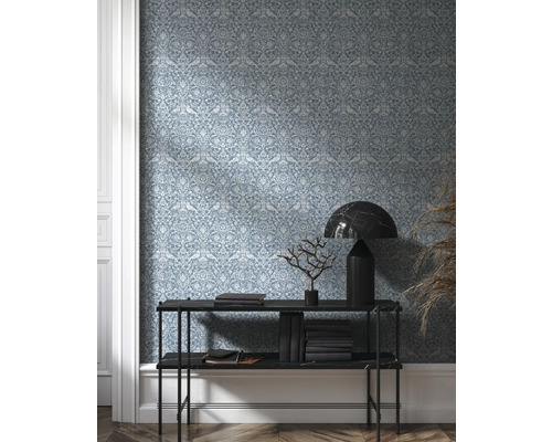 Raumansicht mit gemusterter Tapete, Konsole, Büchern und Dekoration