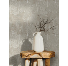 Tapete mit Baummuster auf einer Wand, dazu eine weiße Vase mit Ästen auf einem Holzhocker