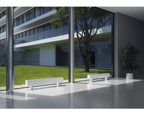 Modernes Gebäude mit weißen Heizkörpern vor einer Fensterfront mit Blick auf einen Garten