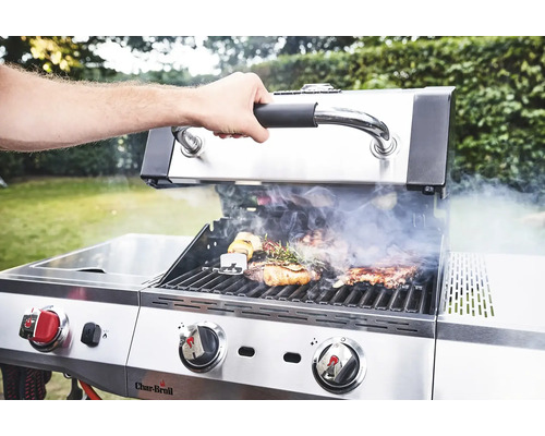 Ein Mann öffnet den Deckel eines Char-Broil Gasgrills, auf dem sich Fleisch und Gemüse befinden.