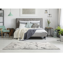Helles Schlafzimmer mit Bett, Teppich und Dekorationen für eine freundliche Atmosphäre.