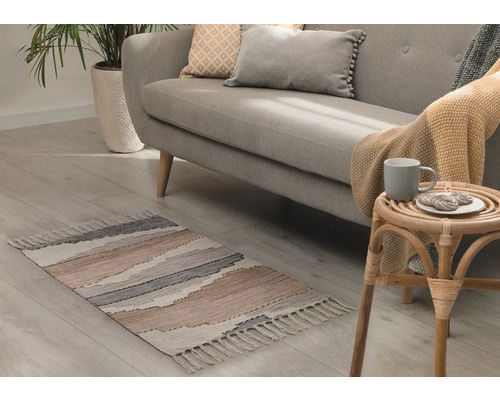 Wohnzimmer mit Sofa, Zimmerpflanze und gemustertem Teppich