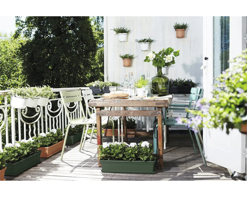 Einladender Balkon mit Tisch, Stühlen und bepflanzten Blumenkästen