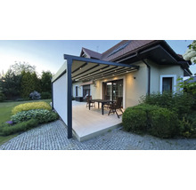 Terrasse mit Pergola, Tisch und Stühlen vor einem Haus.