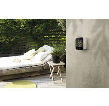 Szene im Garten mit digitalem Thermometer an der Wand.